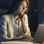 Woman working on a laptop in an office at dusk